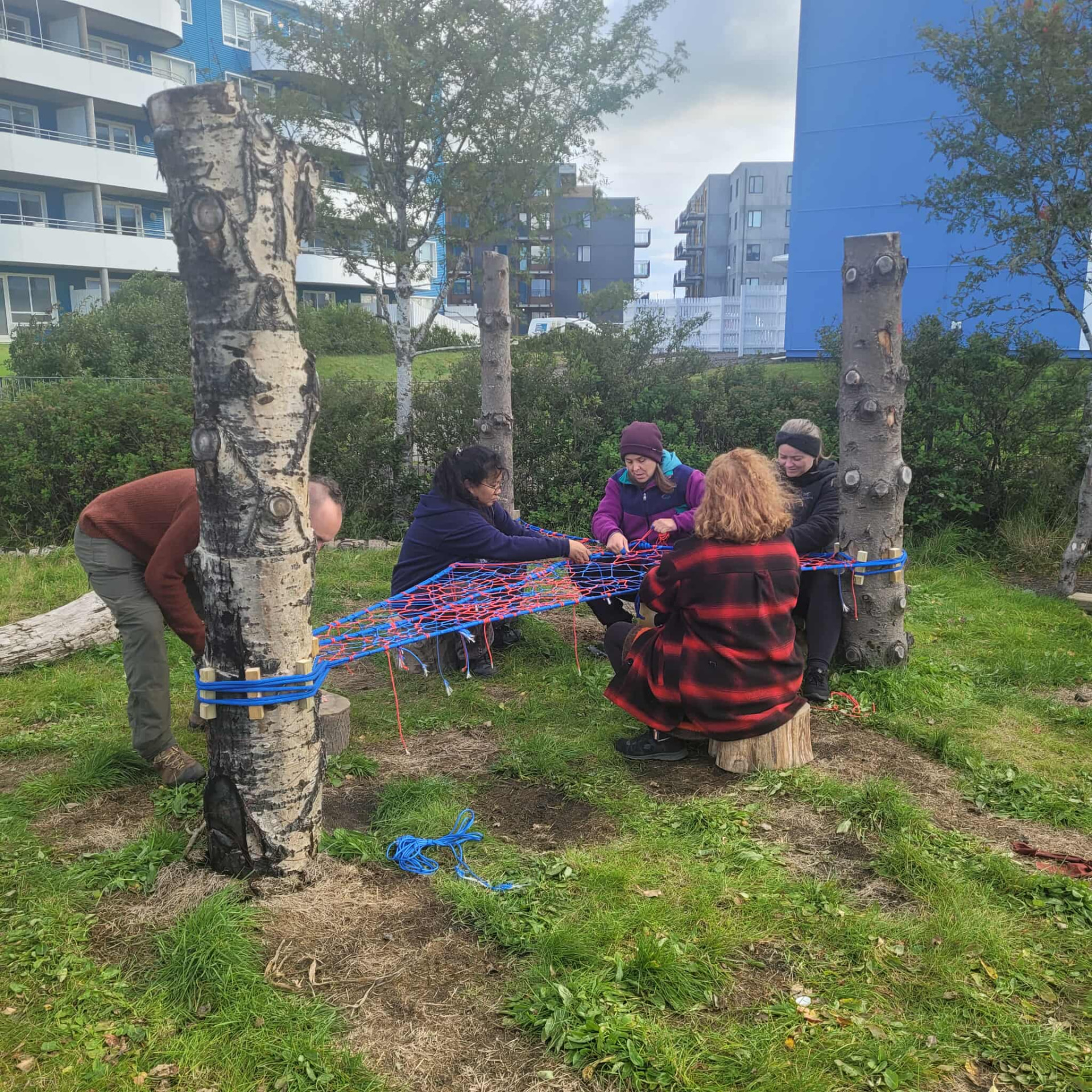Group weaving a blue and red rope TreeNet between trees during a Westdale Junior School training session