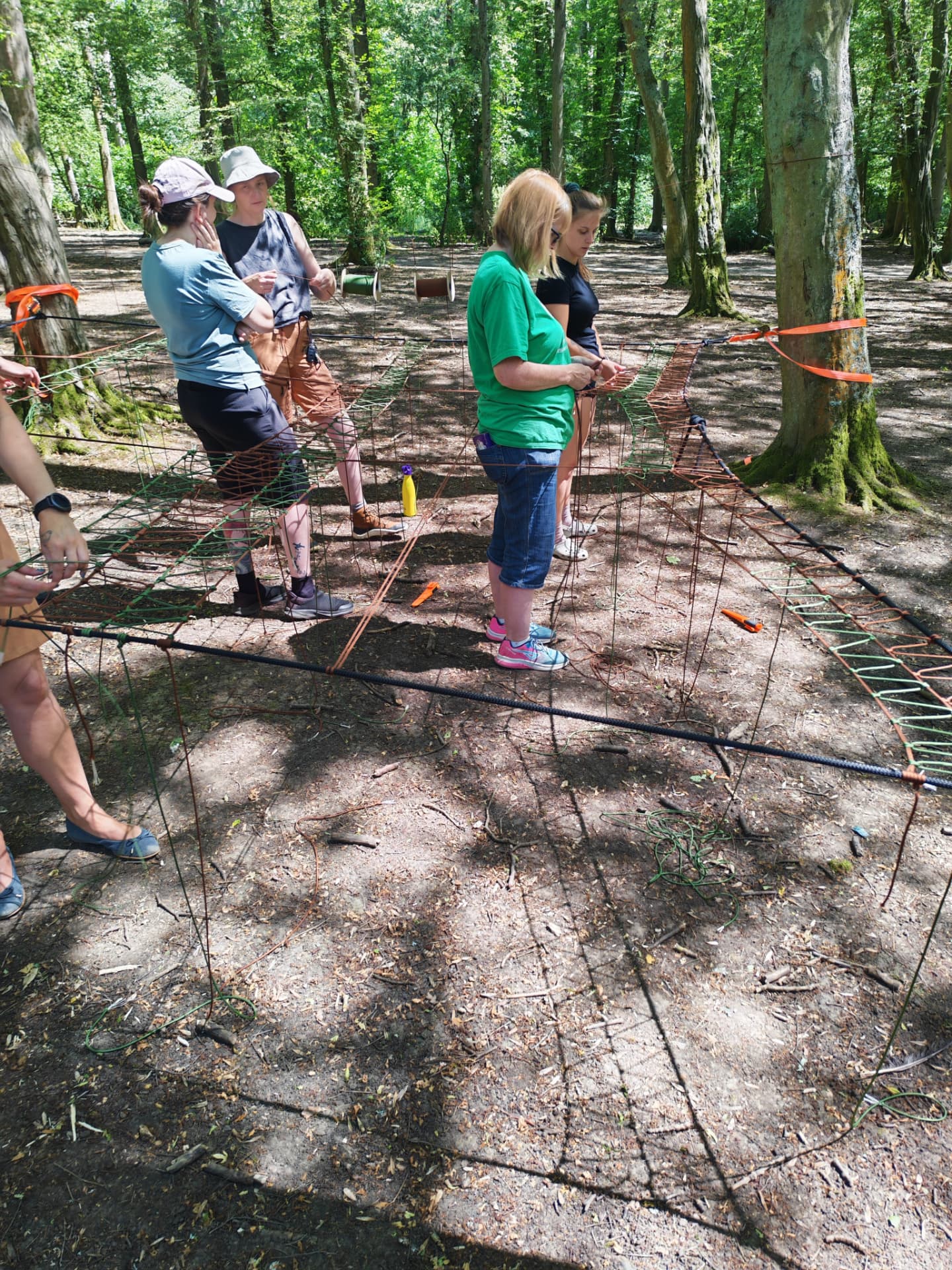 Group hand-weaving net panels during a TreeNet build in the woods