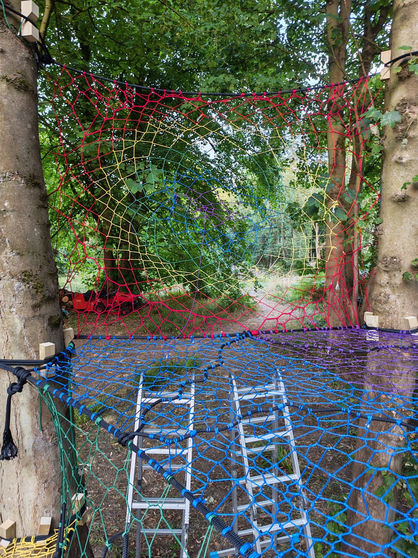 Wide view of the rainbow spider-web net wall above the blue platform net at Halkyn Woods
