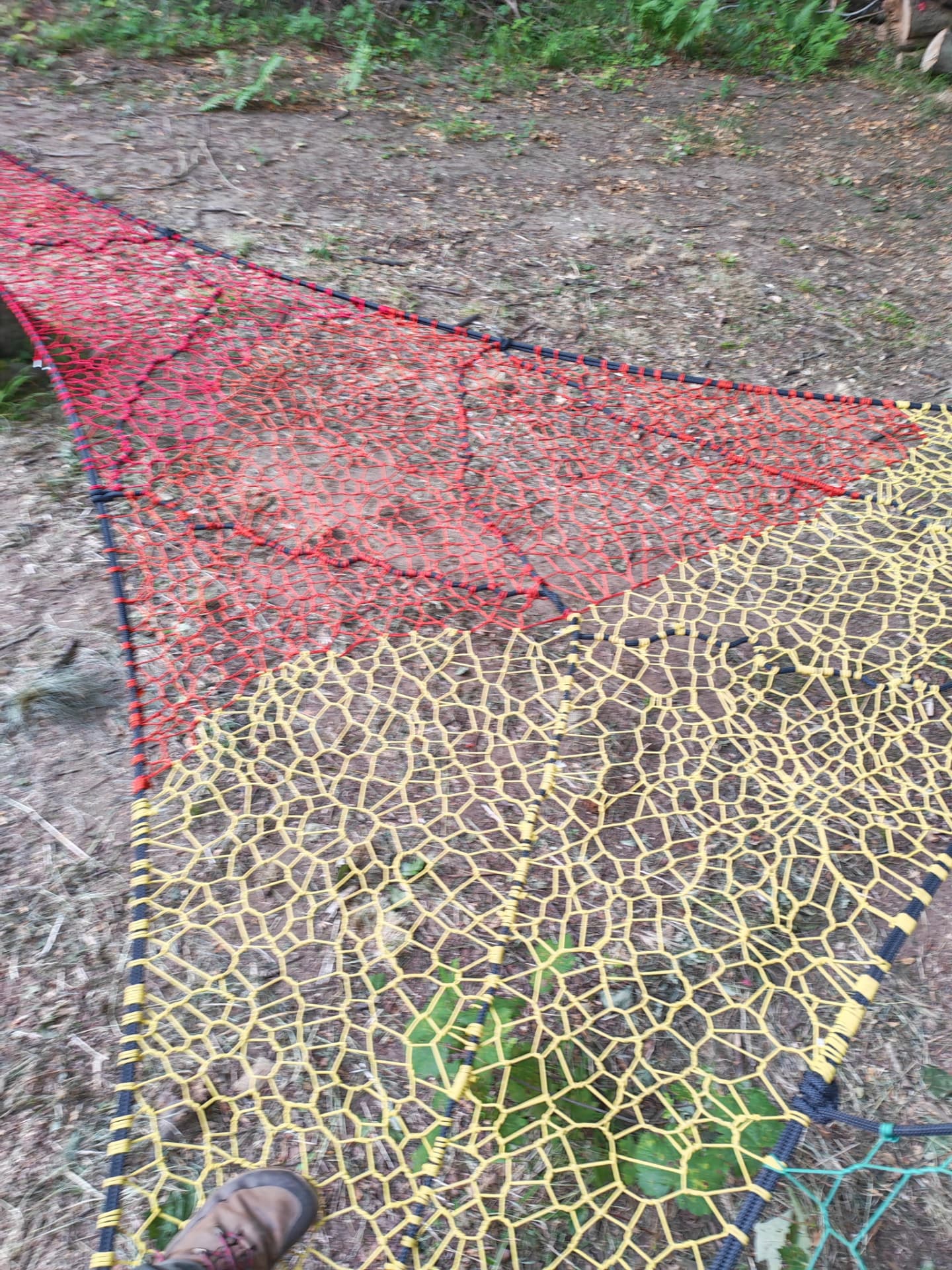Close view of the red and yellow hand-woven net panels of the Halkyn Woods TreeNet